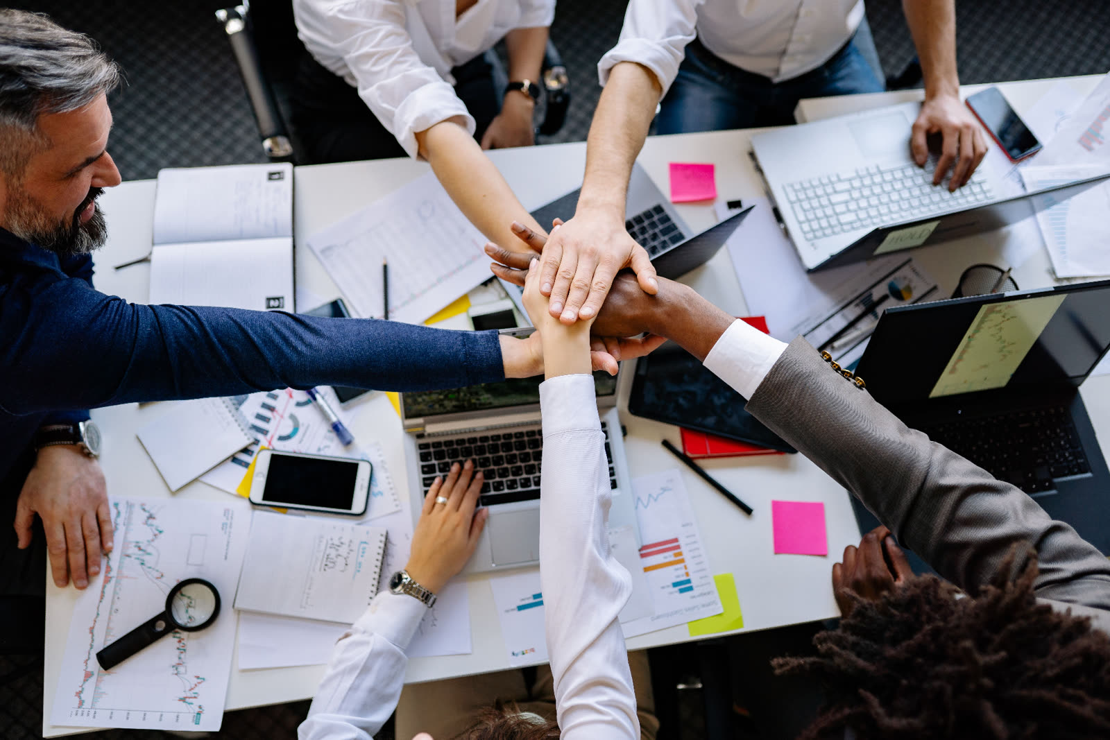 Community partners joining hands together around a table